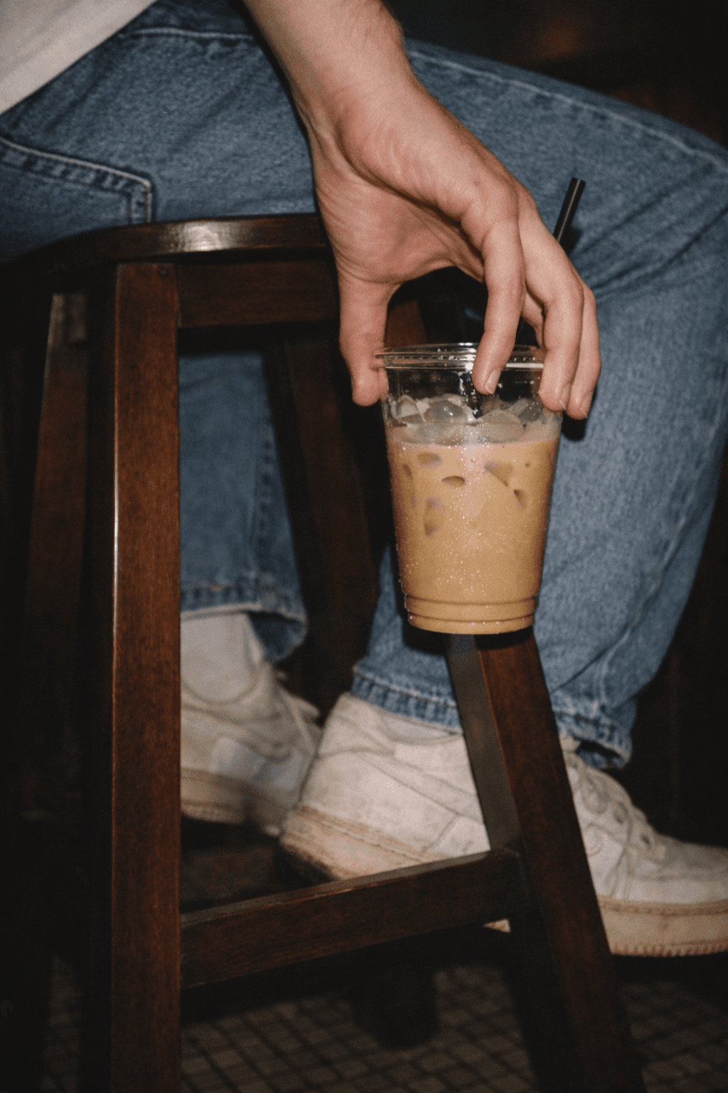 An iced coffee held beside a chair.