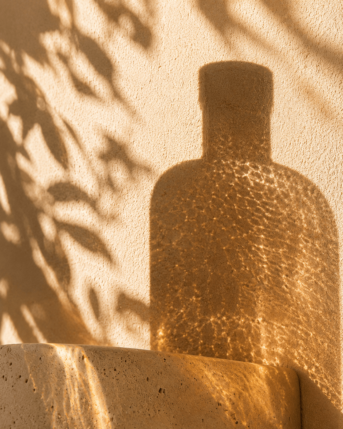 Bottle shadow projected on textured plaster.