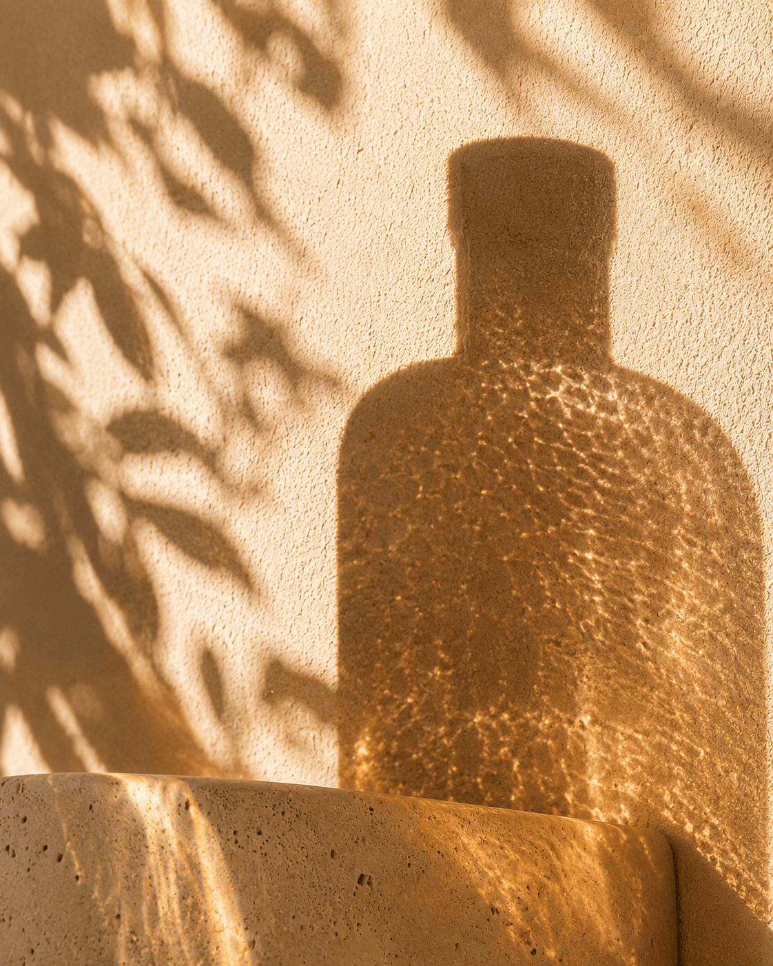 Bottle shadow projected on textured plaster.