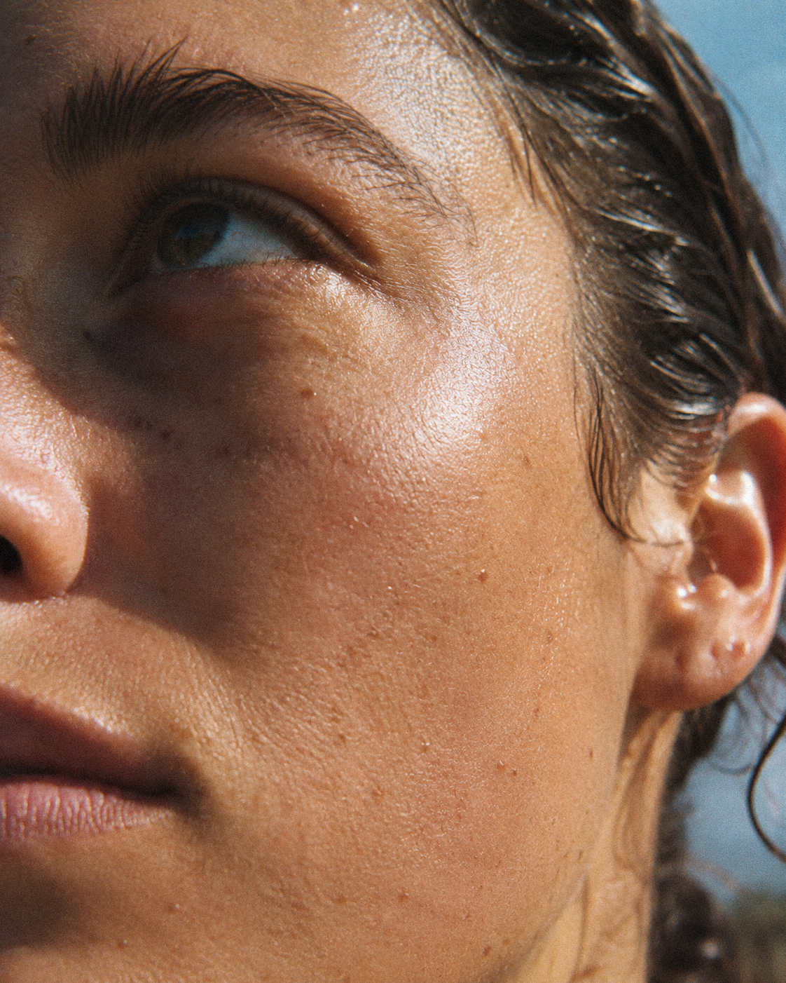 A tactile close-up of sunlit skin and facial texture.
