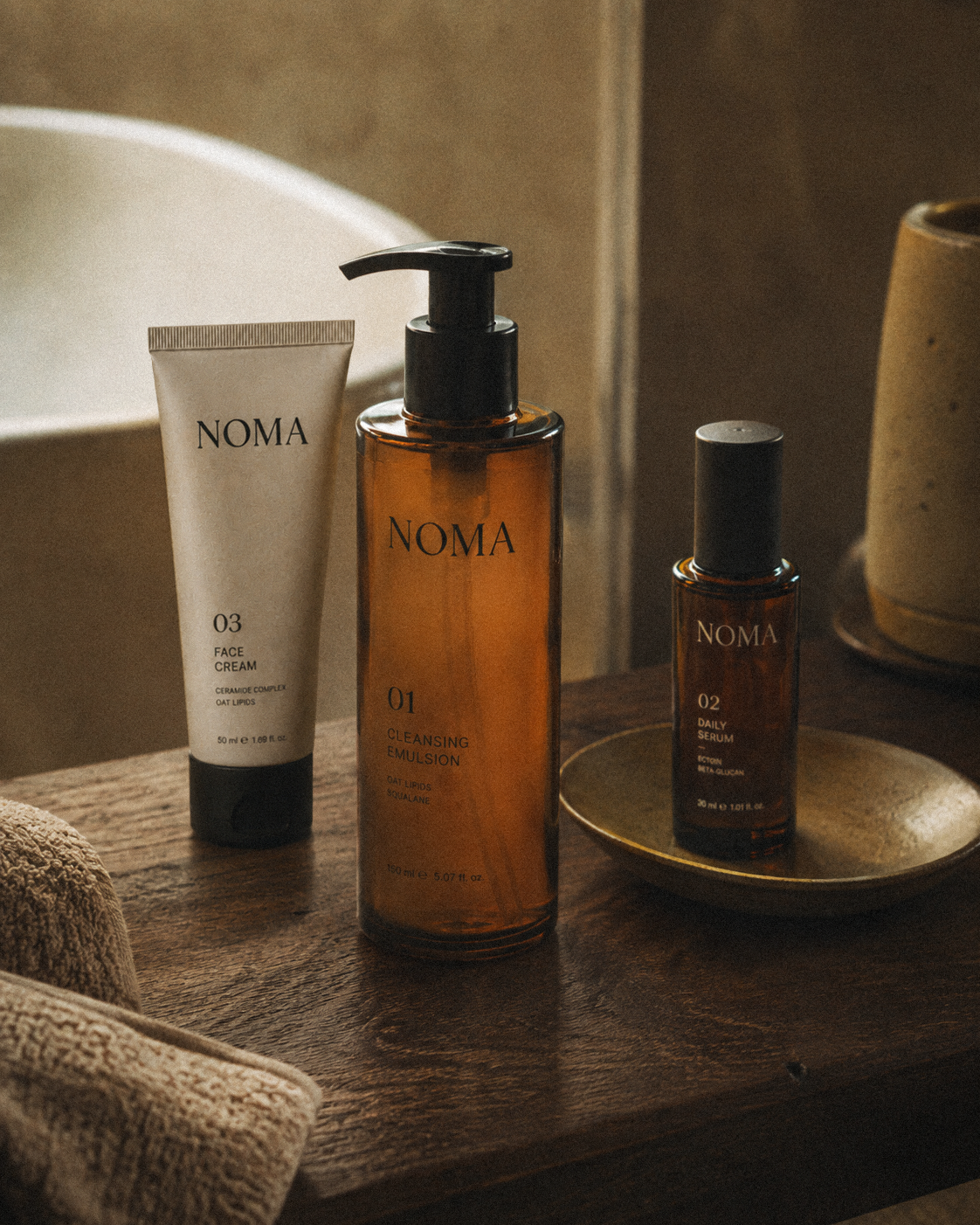 NOMA skincare products arranged in warm bathroom light.
